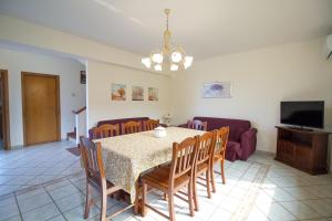 a dining room with a table and chairs and a tv at Etna Villa Alba Chiara in Trecastagni