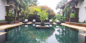 einen Pool mit Stühlen und einer Palme darin in der Unterkunft Eureka Villas Siem Reap in Siem Reap