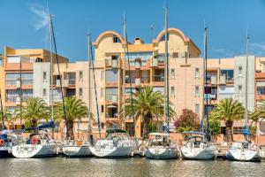 a group of boats docked in front of a building at Appartement et Studio Le Méditerranée Port Soleil in Gruissan