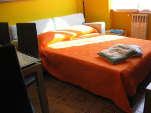奧斯塔的住宿－au montfleury，一间卧室配有一张带橙色毯子的床和一张书桌