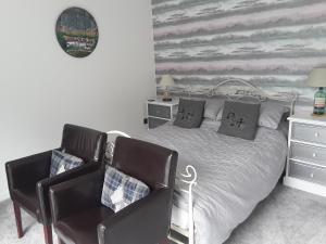 a bedroom with a bed, chair, desk and a television at Morven in Dufftown