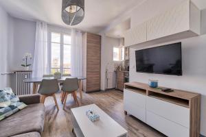 Una sala de estar con un sofá y un televisor de pantalla plana. en Confortable 3 pieces, capitale Paris, en Nogent-sur-Marne