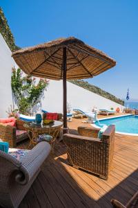 a patio with an umbrella and chairs and a pool at Castri Village Kythira Quality Resort in Agia Pelagia