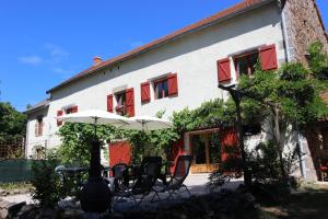 a group of chairs and an umbrella in front of a building at Combrailleurs in Espinasse