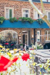 a brick building with a blue roof and flowers in front of it at Landhaus Beth-Steuer in Valwig