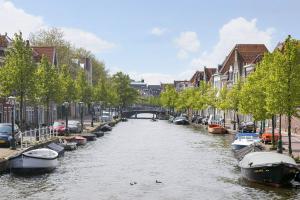 un río con barcos en una ciudad con edificios en Tiny Monumental House in Down Town Leiden, en Leiden
