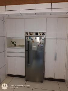 a stainless steel refrigerator in a kitchen with white cabinets at Apartamento com conforto e segurança in Rio das Ostras