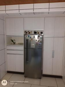 a stainless steel refrigerator in a kitchen with white cabinets at Casa com conforto e segurança in Rio das Ostras