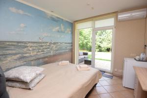 a bedroom with a bed with a painting on the wall at Naujoji Karkle in Karklė