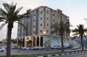 un bâtiment avec des palmiers en face d'un parking dans l'établissement Larissa Suites, à Khobar