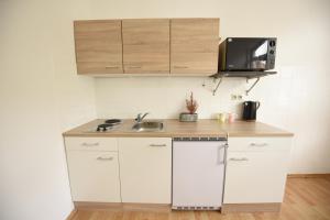 cocina con armarios blancos, fregadero y microondas en Design Apartments 2, en Dortmund