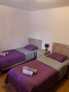 three beds in a room with purple sheets at Tskaltubo Guest House On Mirian Mepe in Tskaltubo