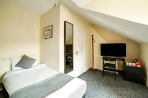 a bedroom with a bed and a flat screen tv at Stratford Hotel in London