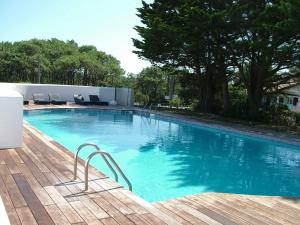 a large swimming pool with a wooden deck at Villa Clara, Résidence face à l'océan et au golf de Chiberta in Anglet