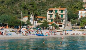 a beach filled with lots of people sitting on the sand at Hotel Fortuna in Hvar