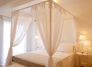 a bedroom with a canopy bed with white curtains at Luxury Villa Eos in vlicha