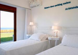 two beds in a white room with a window at Luxury Villa Eos in vlicha +8 photos