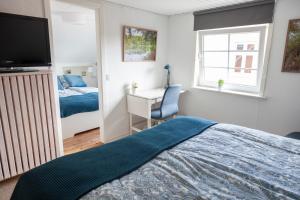 a bedroom with a bed and a desk and a television at Like home Bed & Breakfast in Varde