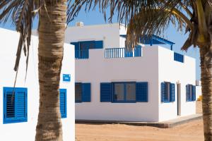 a white building with blue shutters and a palm tree at CALIMAS in Caleta de Sebo