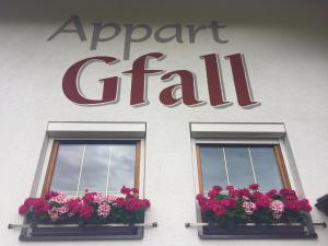 a sign for an airport grill with two windows with flowers at Appart Gfall in Ried im Oberinntal