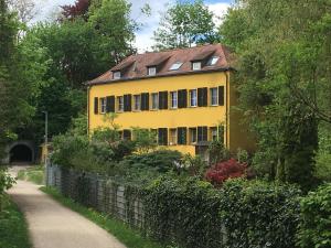 una casa amarilla con una valla al lado de una carretera en Zentrumsnahe Dachwohnung in grüner Oase, en Lauf an der Pegnitz