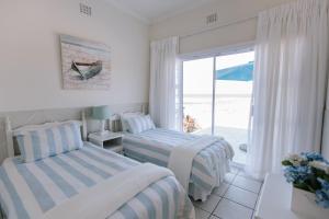 two beds in a bedroom with a view of the ocean at Clifton Cottage in Kei-mouth Village
