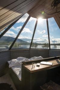 Bett in einem Zimmer mit einem großen Fenster in der Unterkunft Arctic Land Adventure Glass Igloos in Kilpisjärvi