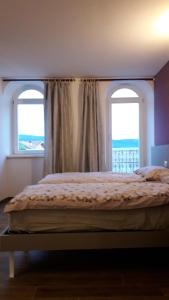 a bed in a bedroom with two windows at ROSTICAFFE' in Lavarone