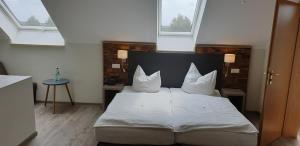 Schlafzimmer mit einem Bett mit weißer Bettwäsche und Kissen in der Unterkunft Landhotel Zum Erbgericht in Stolpen