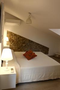een slaapkamer met een wit bed en een stenen muur bij B&B Tra Cielo e Mare in Soverato Superiore