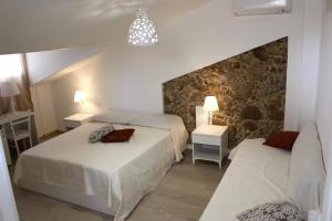 een slaapkamer met 2 bedden en een stenen muur bij B&B Tra Cielo e Mare in Soverato Superiore