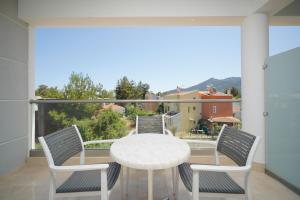 een witte tafel en stoelen op een balkon met uitzicht bij La Santa in Chrysi Ammoudia