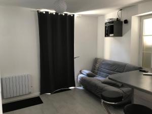- un salon avec un canapé et un rideau noir dans l'établissement Petite maison de Ville, à Auxerre