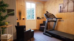 - une salle de sport avec un tapis de course dans une pièce dotée d'une fenêtre dans l'établissement Le Manoir Domaine de la Motte, à Saint-Dyé-sur-Loire