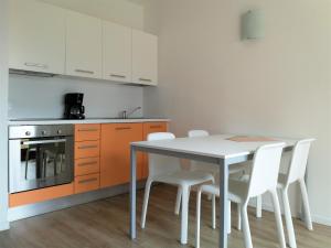 a kitchen with a table and some white chairs at Appartamenti Garda il lago in Riva del Garda