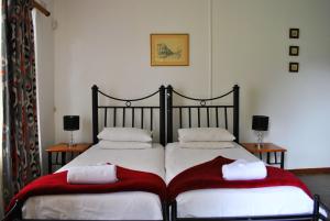 - une chambre avec 2 lits et des couvertures rouges et blanches dans l'établissement Mount Azimbo Lodge, à Louis Trichardt
