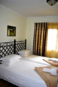 two twin beds in a room with a window at Mount Azimbo Lodge in Louis Trichardt
