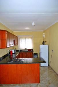 - une cuisine avec des placards en bois et un réfrigérateur blanc dans l'établissement Mount Azimbo Lodge, à Louis Trichardt