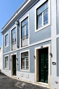 un edificio azul y blanco con puertas verdes en Villa Graça -Hostels and Apartments en Santarém