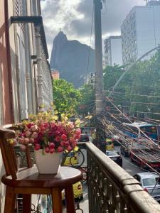 a vase of flowers on a balcony with a view of a city at HMG - Praia de Botafogo in Rio de Janeiro
