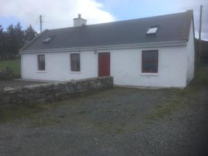 a white house with red doors and a stone wall at Johnny Joe's in Achill