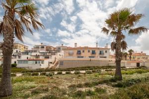 two palm trees in front of a building at Stunning TH2 with Sea View in Casal da Lagoa Seca