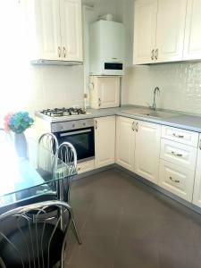 a kitchen with white cabinets and a table and a stove at Skyline Rooftop Condos in Oradea