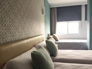 a hotel room with two beds and a window at Hotel Nómadas in Vejer de la Frontera