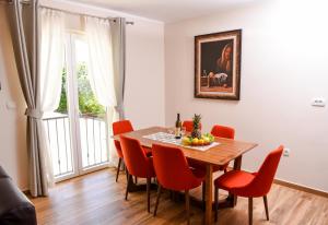 a dining room with a wooden table and red chairs at Apartments Balbo in Bijela