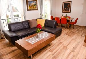 un soggiorno con divano in pelle nera e tavolino da caffè di Apartments Balbo a Bijela