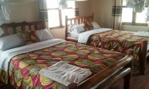 two beds sitting next to each other in a bedroom at Tembo Safari Lodge in Katunguru