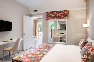 a bedroom with a bed and a desk and a window at Alexandra Beach Spa Resort in Potos