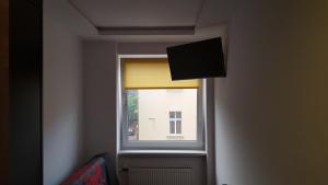 ventana con cortina amarilla y TV en StudioSpanie beach room small en Sopot