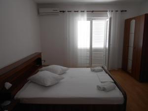 een slaapkamer met een bed met 2 kussens en een raam bij Apartments Panorama in Korčula